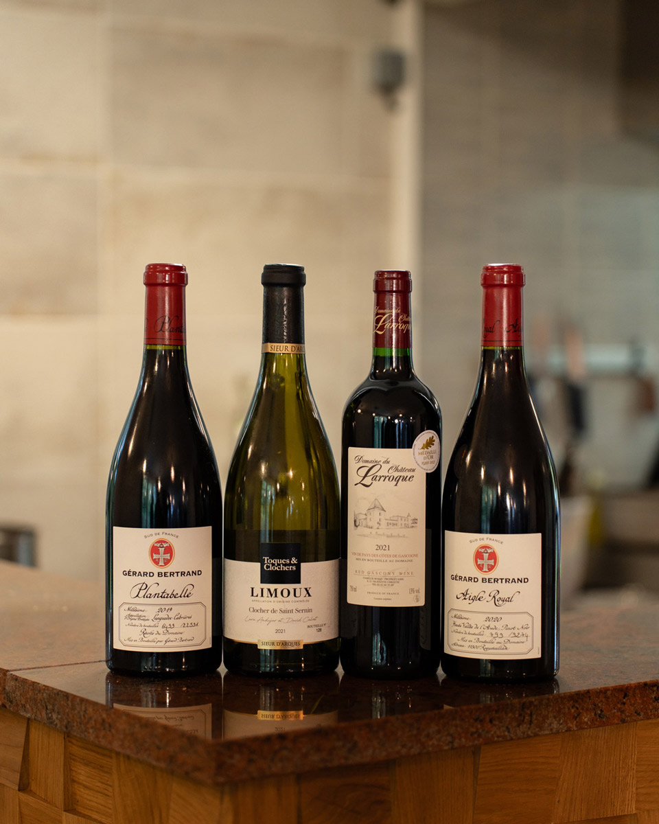 Quatre bouteilles de vins sélectionnées par le chef pour son accord mets et vin disposées sur le comptoir